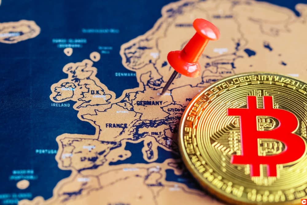 Un bitcoin posé sur une carte de l'Europe, avec l'Allemagne épinglée