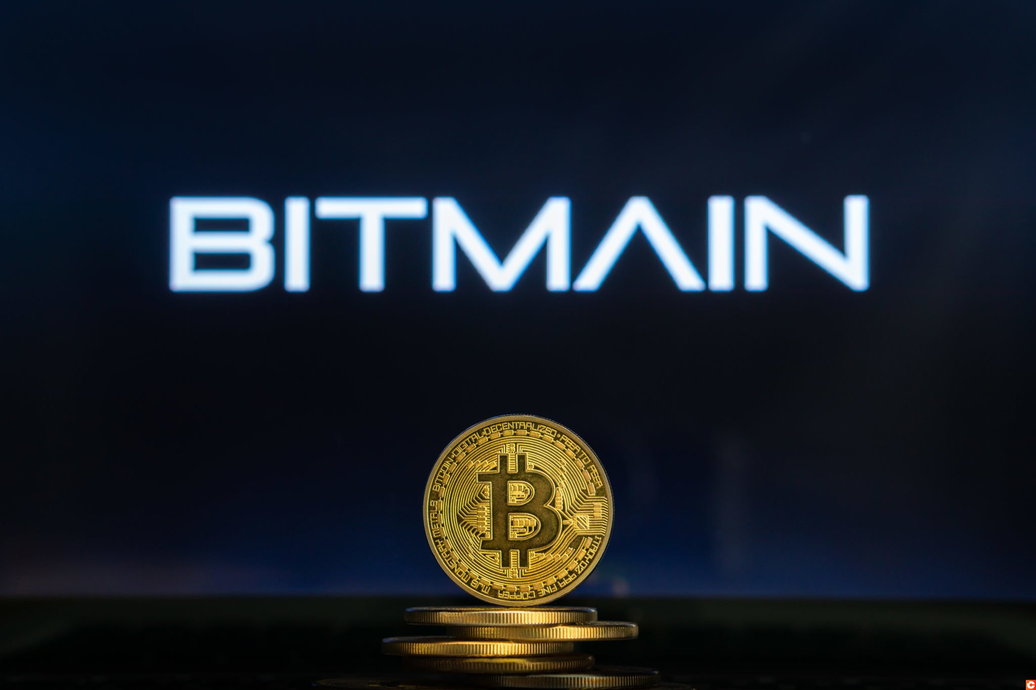 Bitmain logo on a computer screen with a stack of Bitcoin cryptocurency coins.