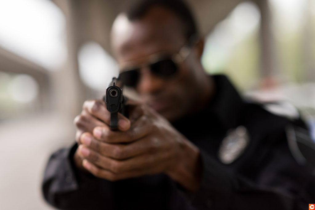 closeup shot of handgun in hands of african american policeman