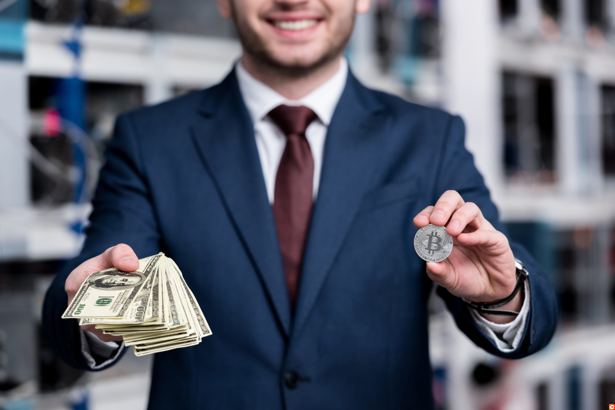 cropped shot of businessman holding stack of cash and bitcoin at cryptocurrency mining farm