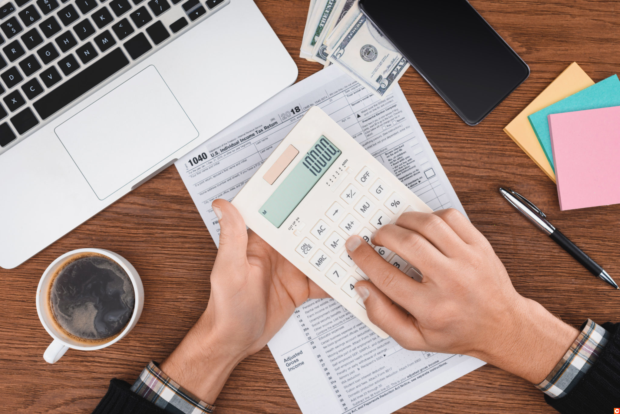 cropped view of man using calculator with tax form and laptop on background