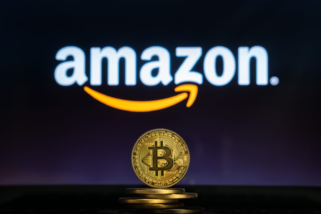 Amazon logo on a computer screen with a stack of Bitcoin cryptocurency coins.