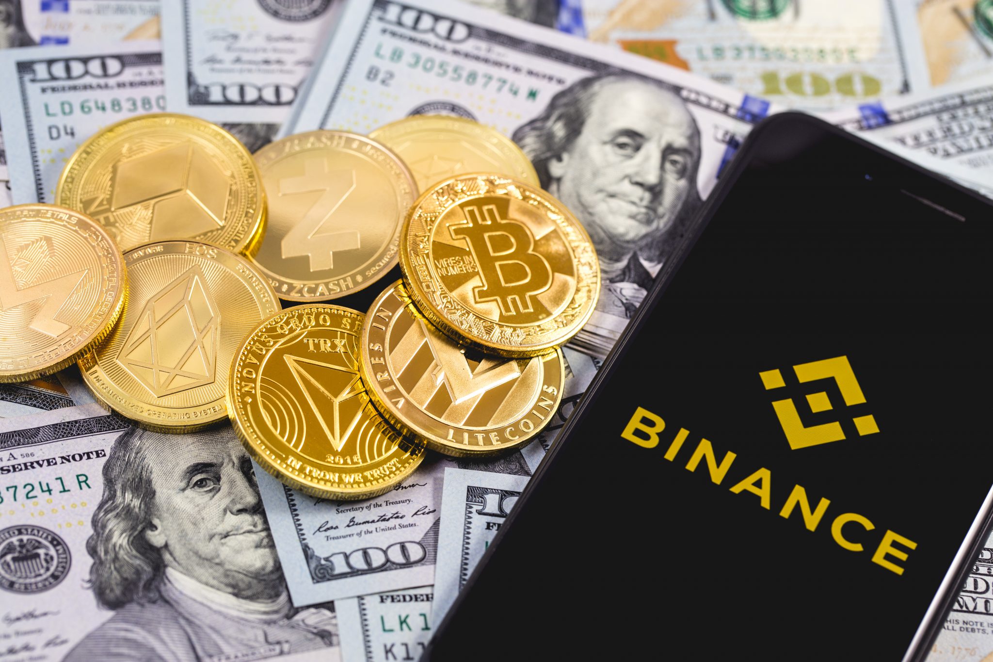 Apple iPhone and Binance logo, and dollars with cryptocurrency. Binance is a cryptocurrency exchange. Ekaterinburg, Russia - September 19, 2018