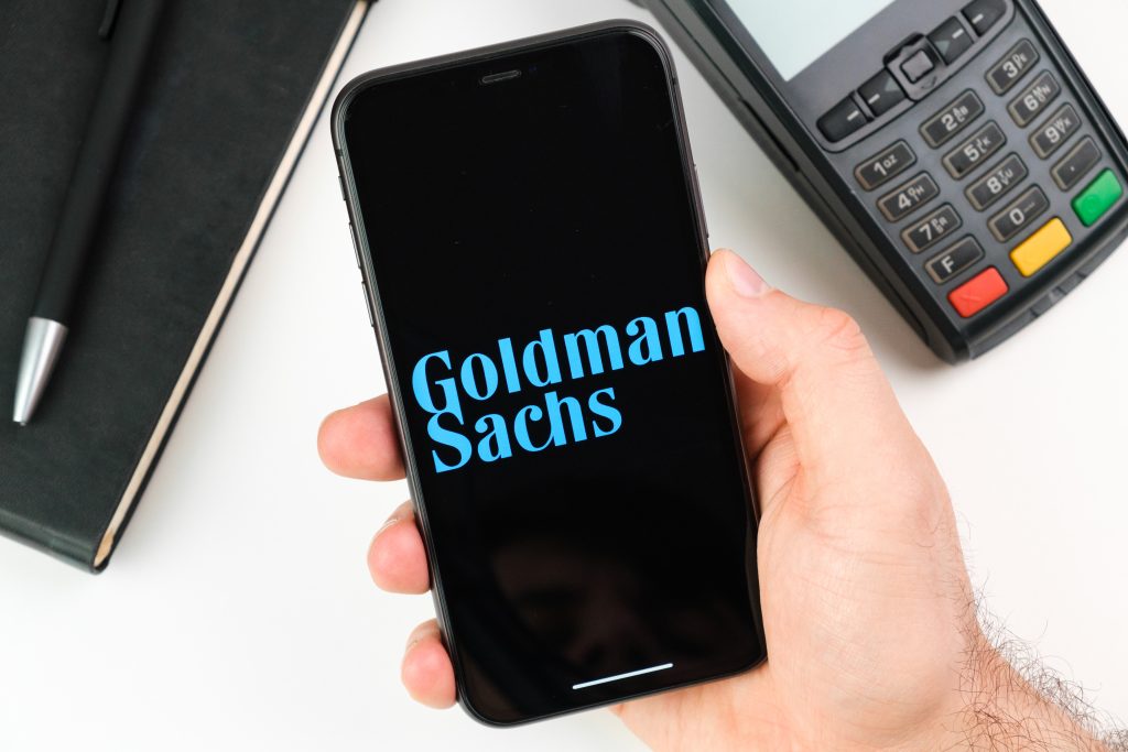 Goldman Sachs bank logo on the black smartphone screen in mans hand on the background of payment terminal, May 2021, San Francisco, USA