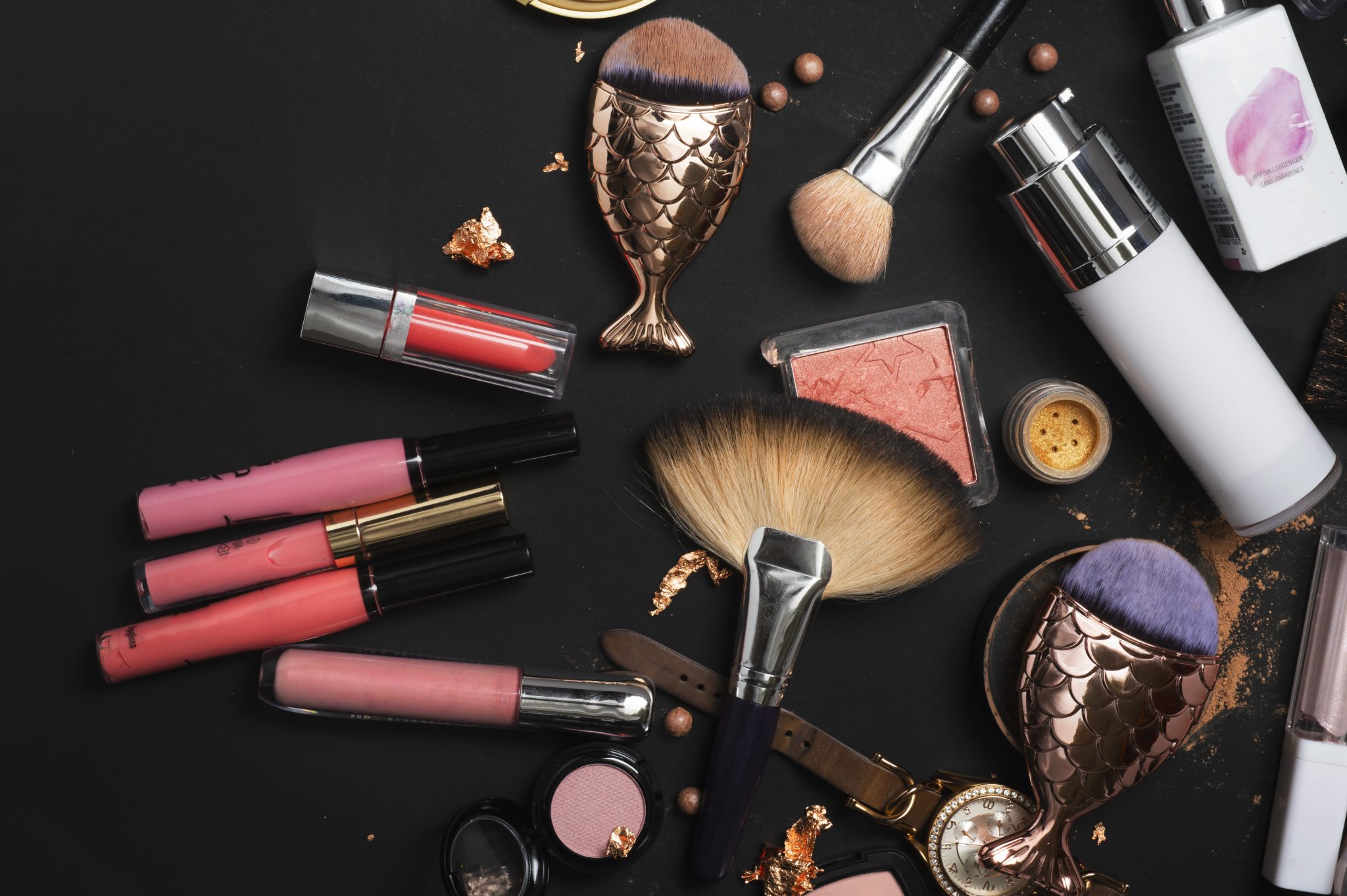 Set of luxury cosmetics with makeup brushes on black background