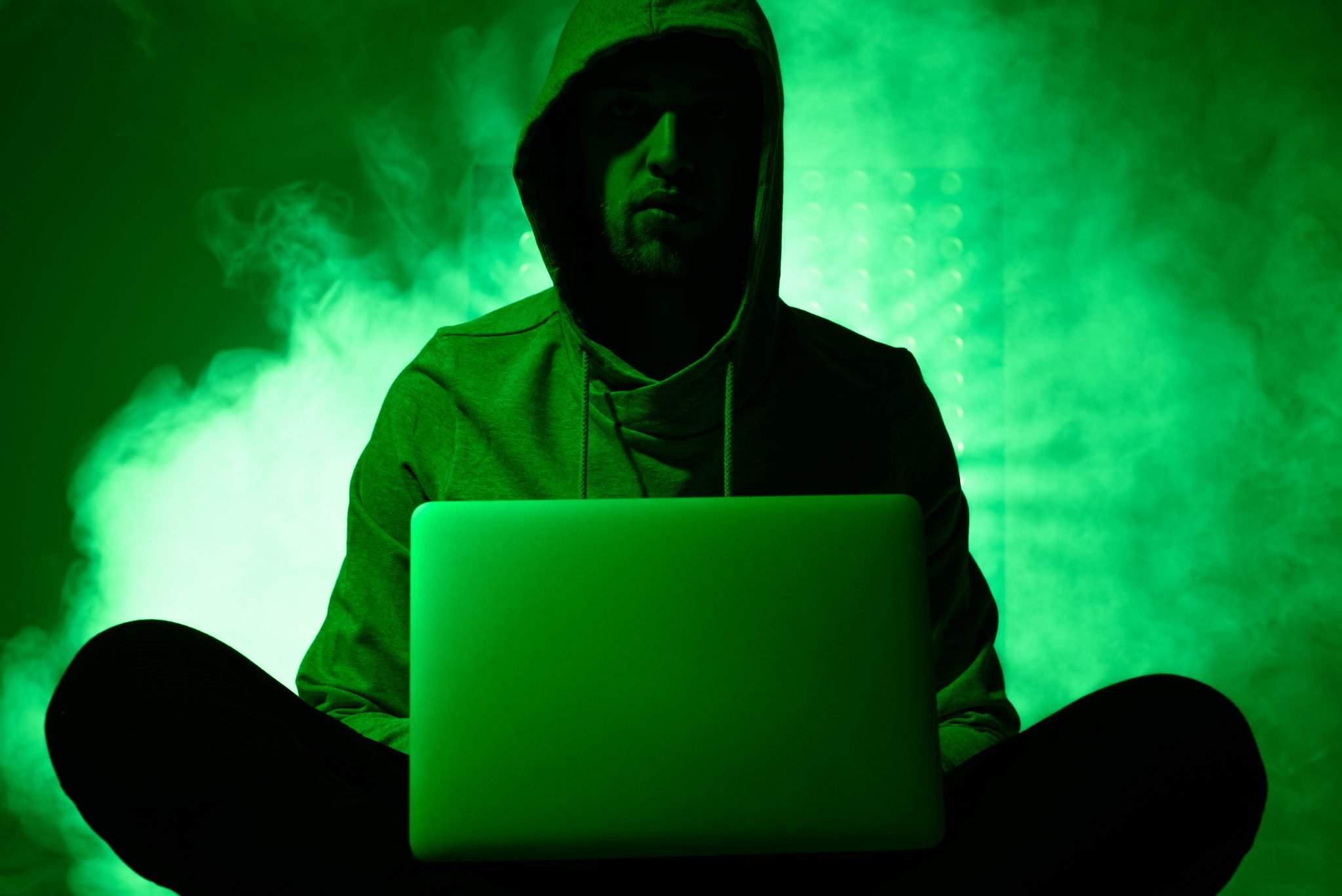 toned picture of hacker in hoodie with laptop