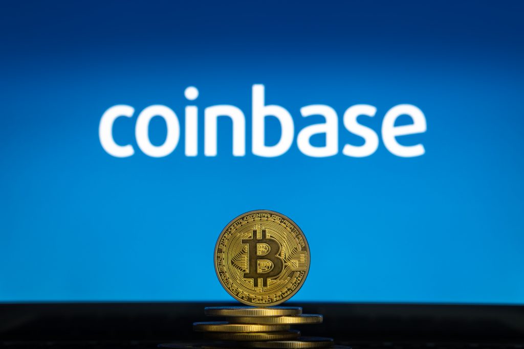 Coinbase logo on a computer screen with a stack of Bitcoin cryptocurency coins.