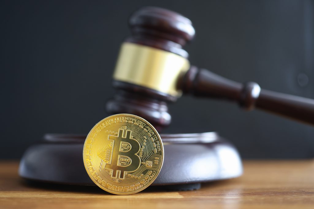 Gold coin bitcoin lying next to judge hammer closeup