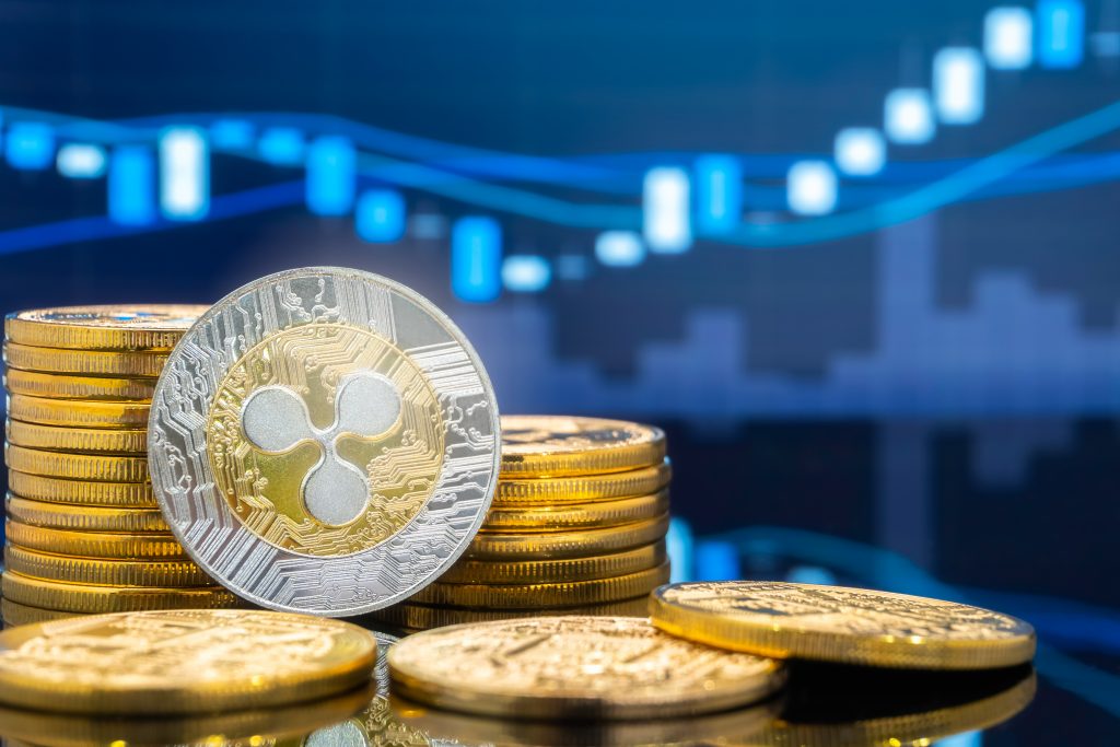 Ripple (XRP) and cryptocurrency investing concept - Physical metal Ripple coins with global trading exchange market price chart in the background.