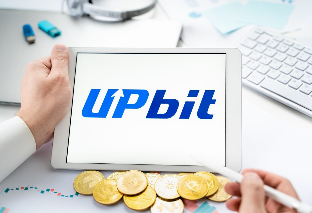 Russia Moscow 06.05.2021.Businessman with tablet.Logo of cryptocurrency stock exchange Upbit.Trading blockchain platform to buy,sell digital crypto coins,tokens Bitcoin,Ethereum.Business,investing.