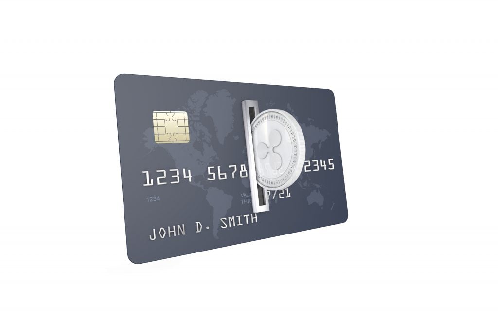 Silver Ripple Coin (XRP) being inserted into coin acceptor on a credit card. Ripple Upload to Bank Account Concept.