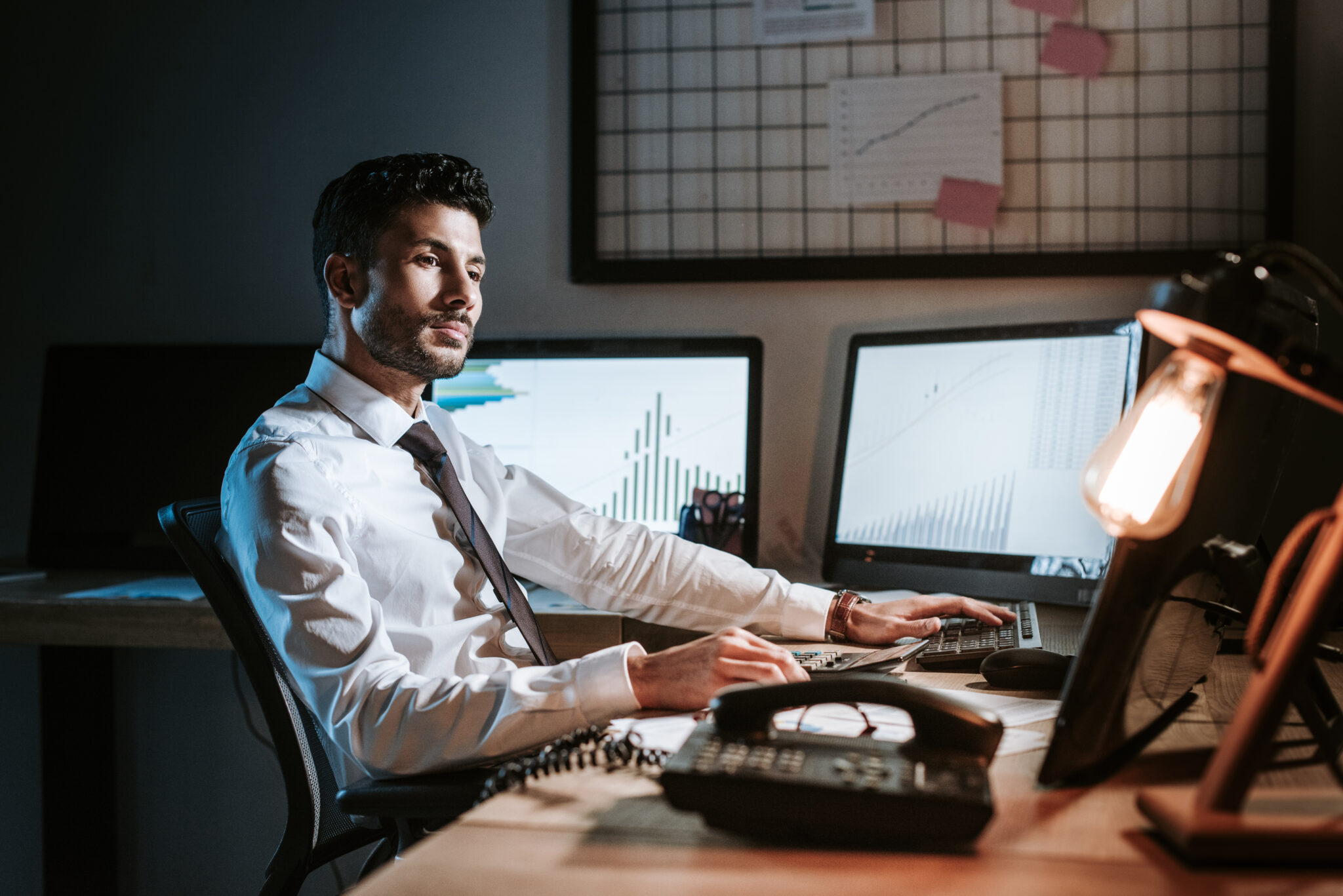 bi-racial trader sitting at table and looking away in office