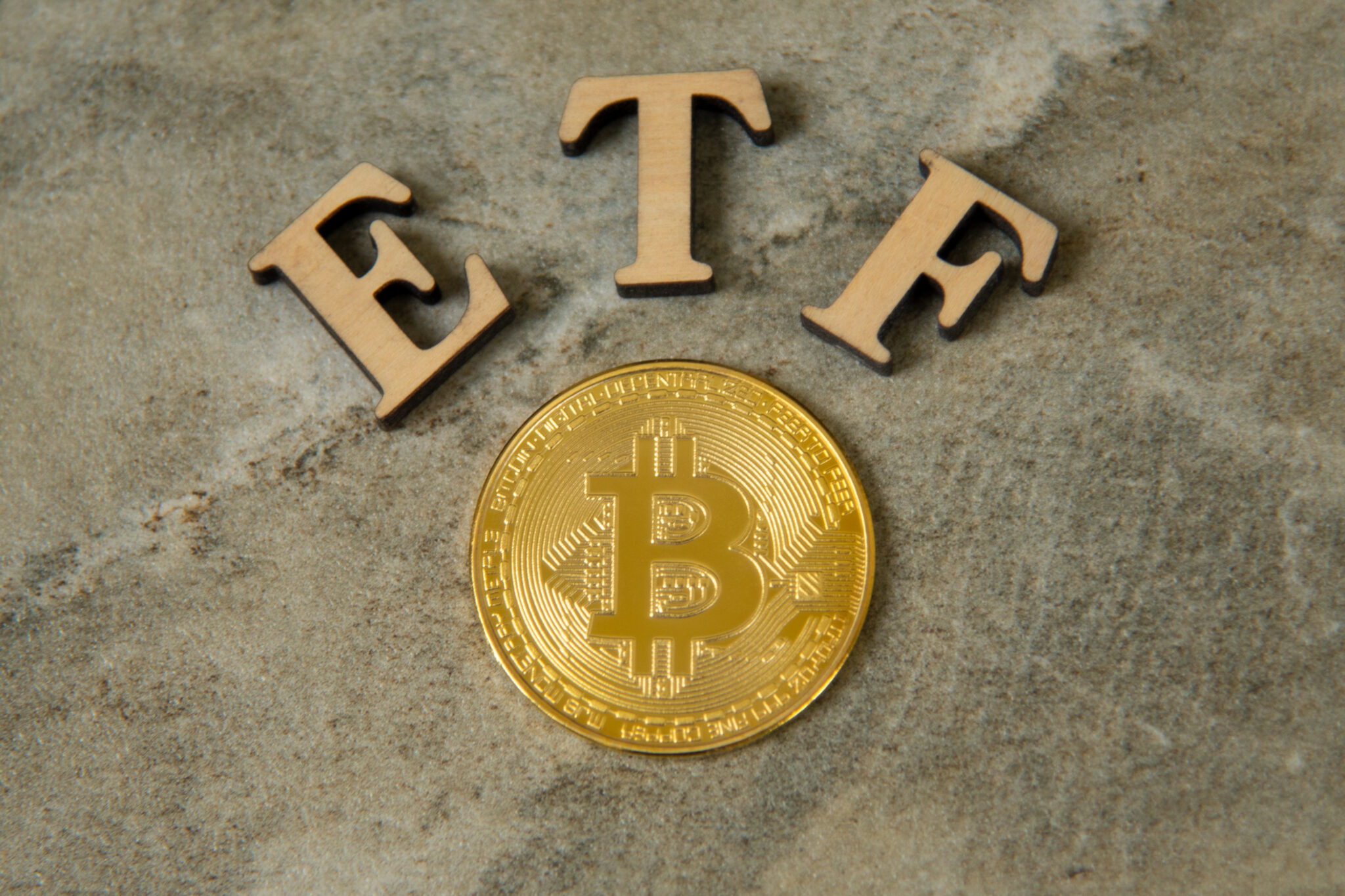 Bitcoin coin with ETF text on stone background