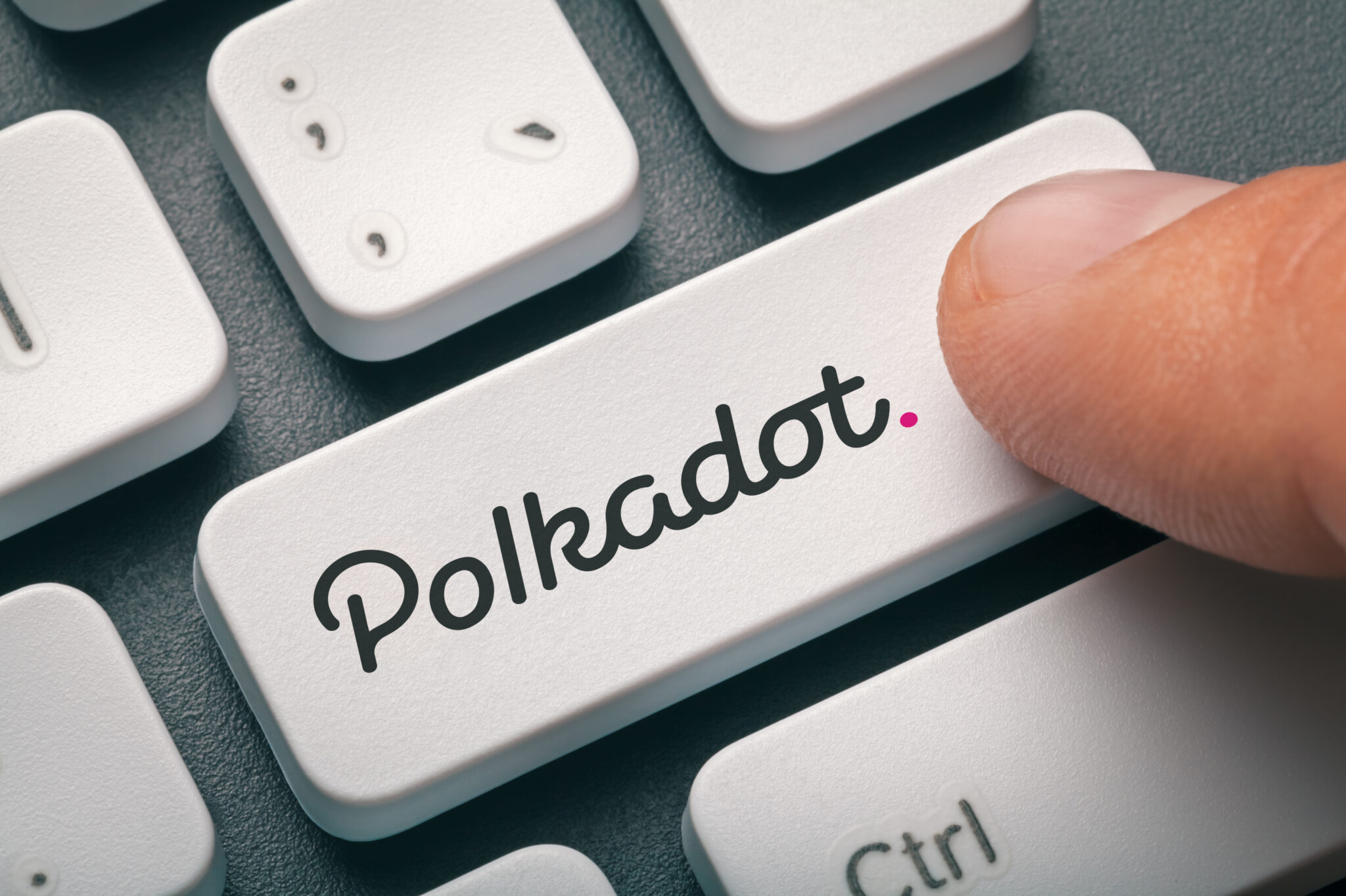Cryptocurrency trading concept: Male hand pressing computer key with Polkadot | Dot logo. Cryptocurrency mining, trading, market concept.