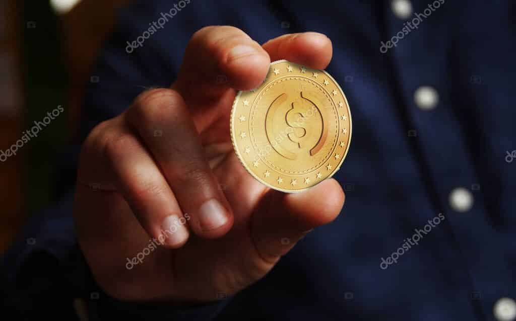 USDC cryptocurrency symbol golden USD coin in hand abstract concept.