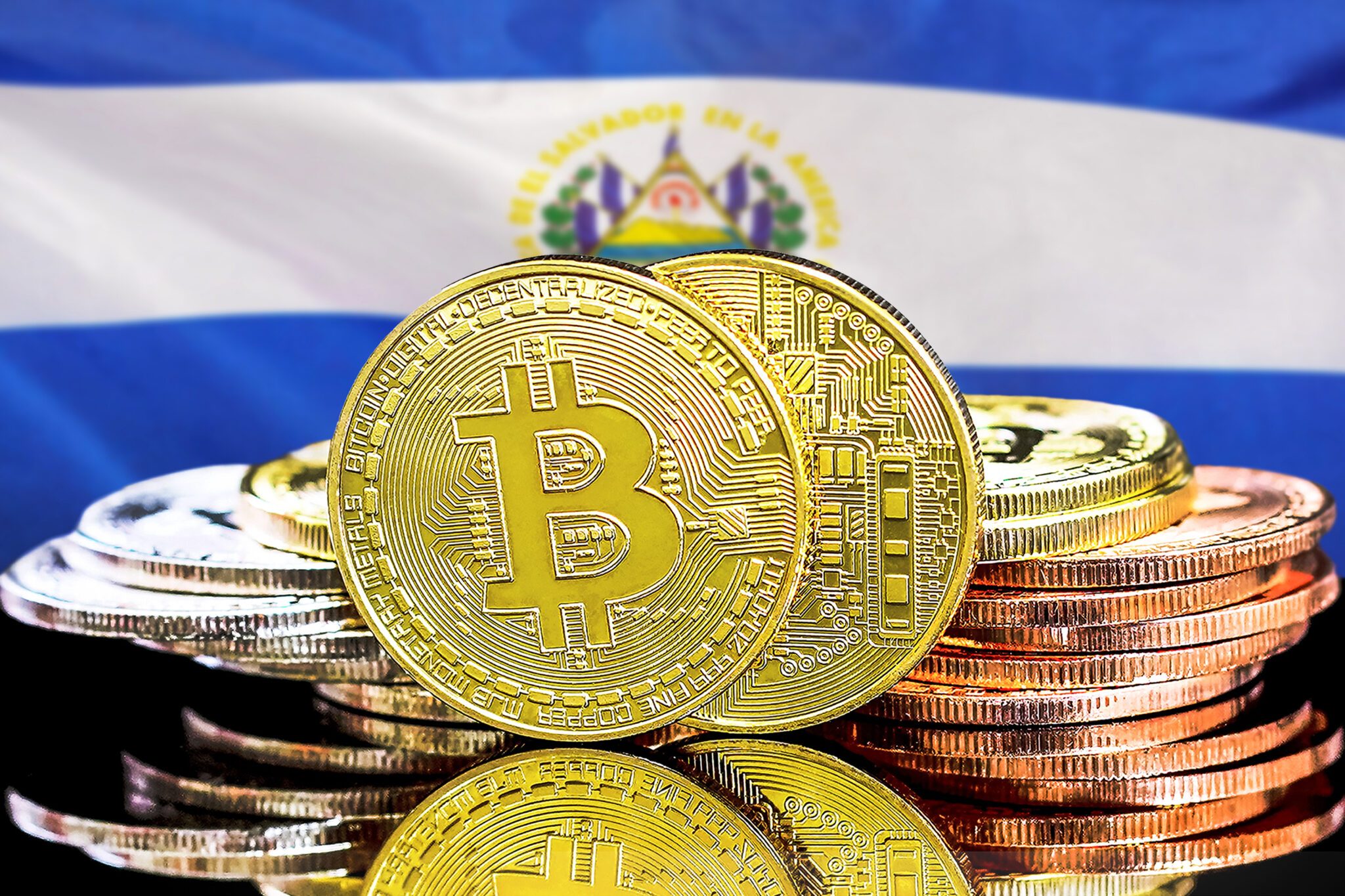 Concepto para inversionistas en criptomoneda y tecnología Blockchain en El Salvador.  Bitcoins en el fondo de la bandera de El Salvador