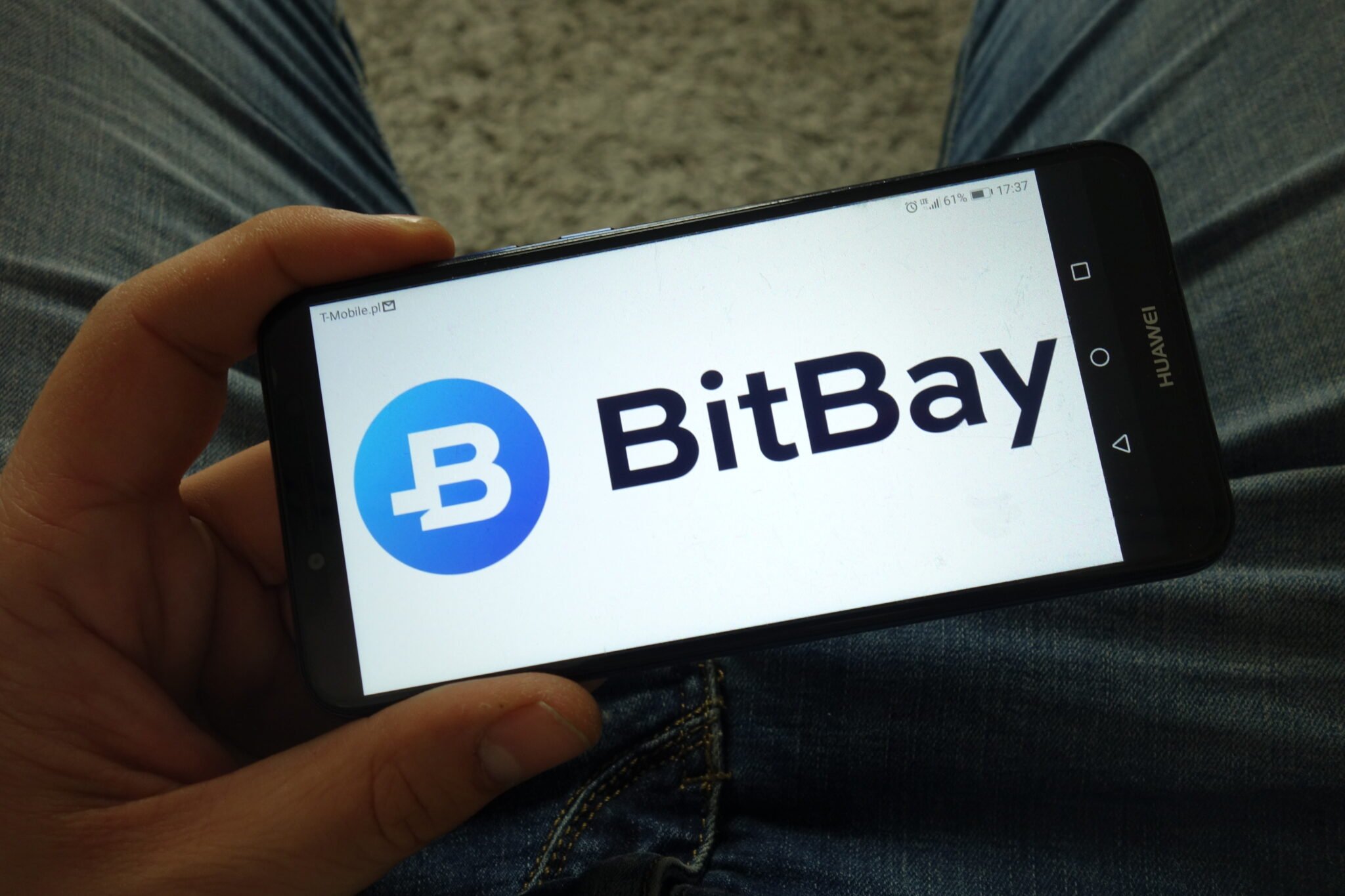 KONSKIE, POLAND - March 31, 2019: Man holding smartphone with BitBay cryptocurrency exchange logo