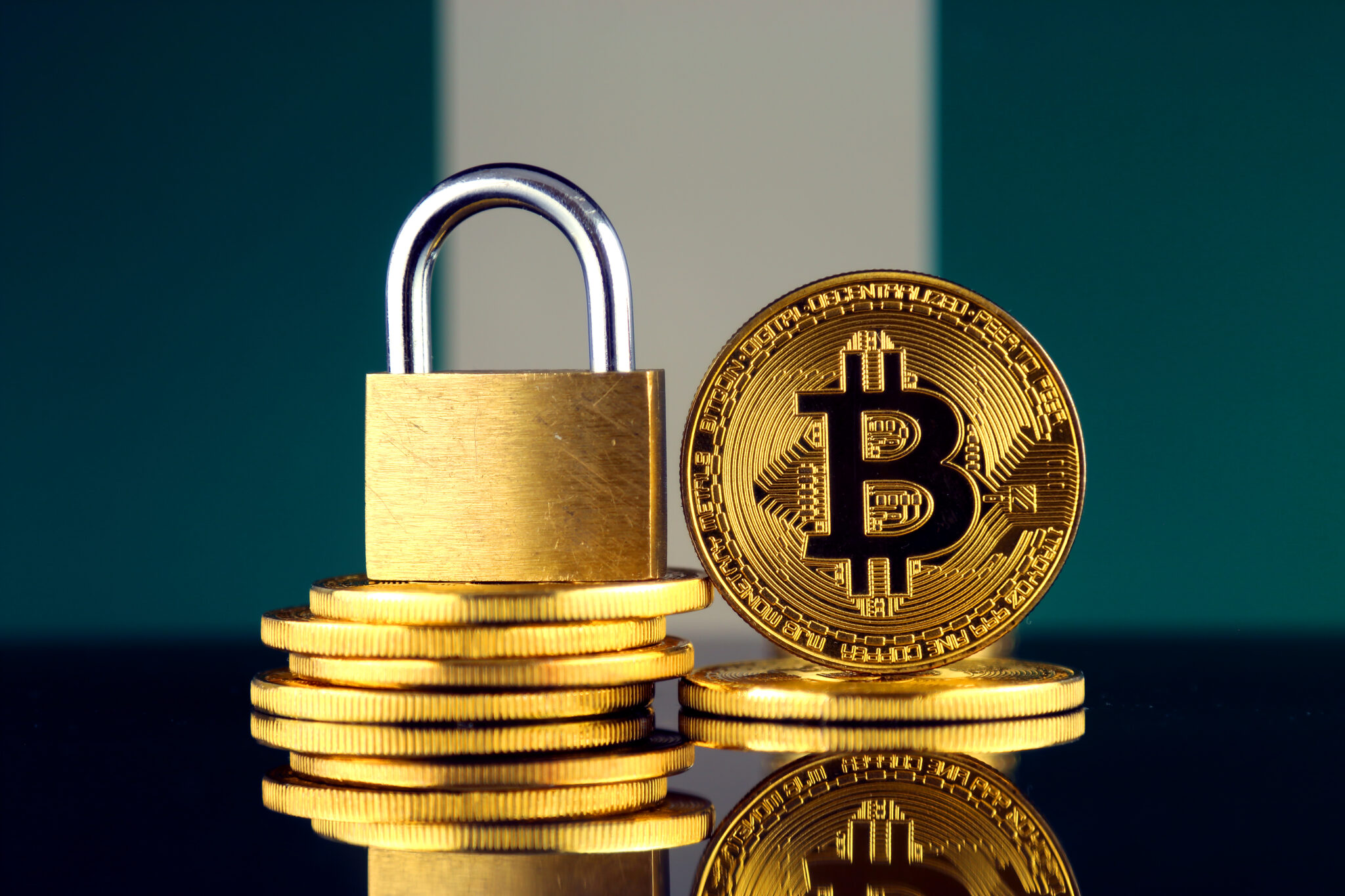 Des bitcoins empilés sous un cadenas doré.