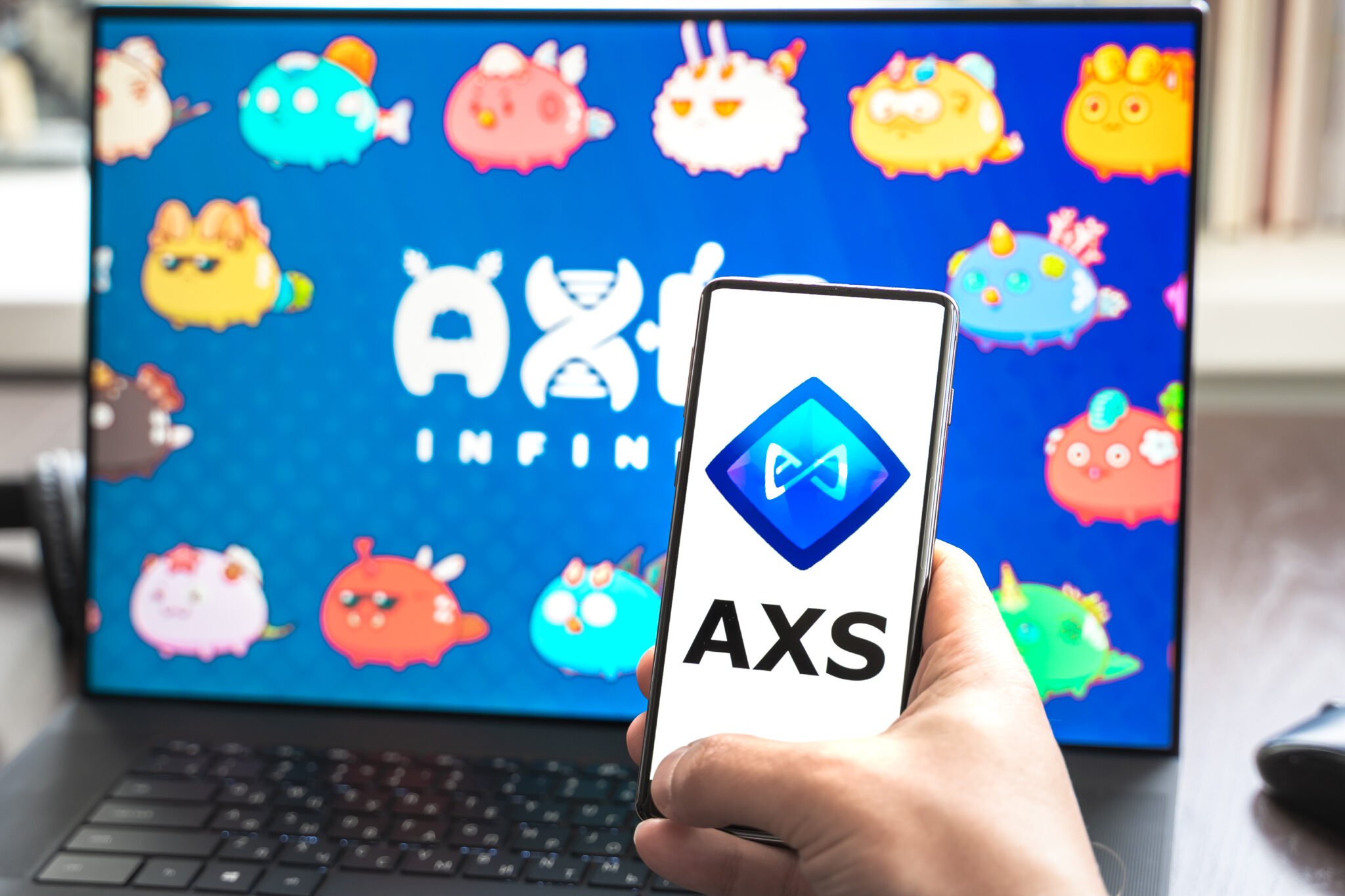 Russia Moscow 30.05.2021.Logo,screenshot of blockchain nft ethereum cryptocurrency game Axie in laptop,mobile phone.Man playing,collecting,creating crypto pet,heroes. Earning digital money tokens AXS.