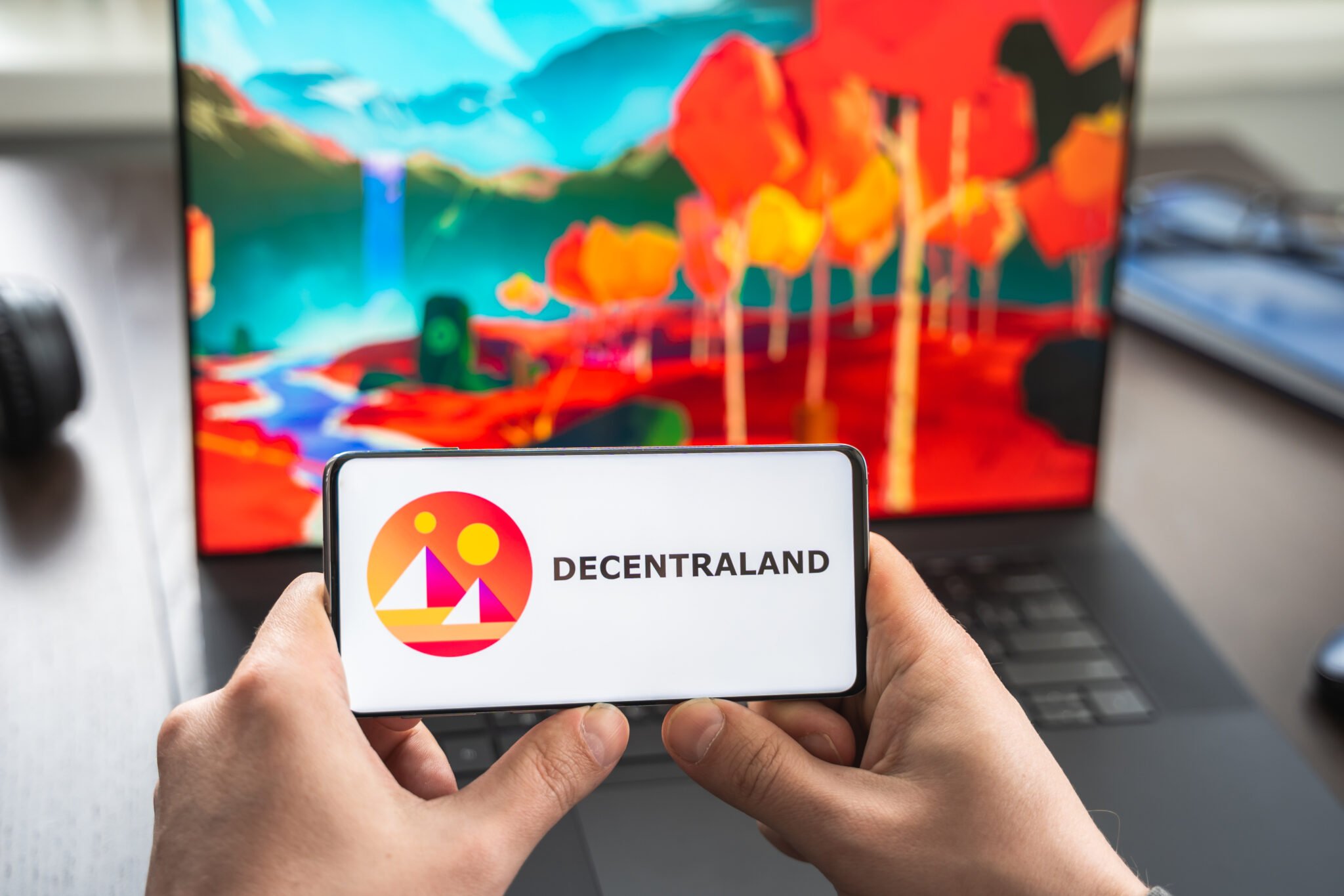 Russia Moscow 30.05.2021.Logo,screenshot of blockchain nft ethereum cryptocurrency game Decentraland in laptop,mobile phone.Man playing with crypto coins,token MANA.Earning digital money.Lands,heroes.