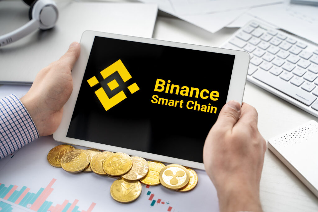 Businessman holding tablet with logo of cryptocurrency decentralized exchange protocol Binance Smart Chain. Trading blockchain platform to buy, sell, change crypto coins, tokens, diital money.