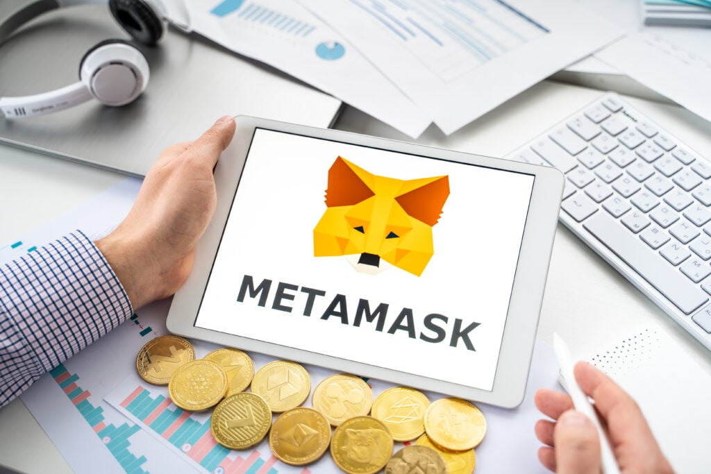 Russia Moscow 06.05.2021 Businessman, tablet. Logo of software cryptocurrency wallet,gateway Metamask. Blockchain application to buy,store,send,swap crypto coins,digital tokens. Bitcoin,Ethereum.