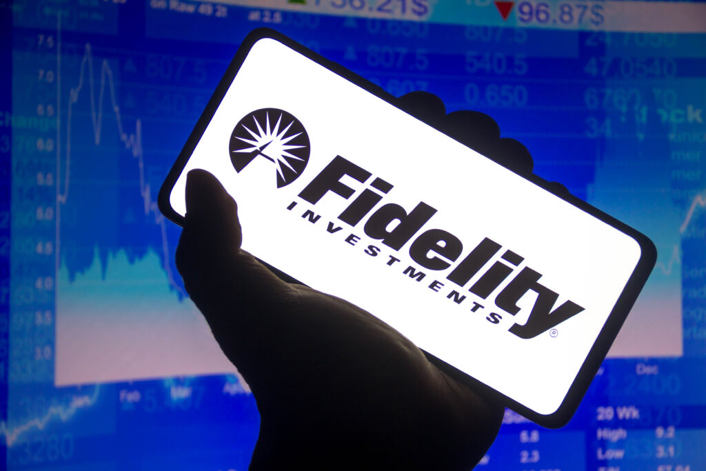 November 15, 2021, Brazil. In this photo illustration the Fidelity Investments logo displayed on a smartphone screen and a stock market graph in the background