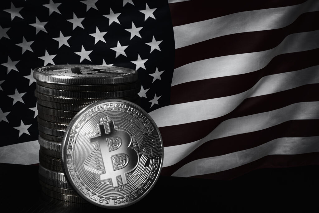 One silver bitcoin and stack of bitcoins over USA flag