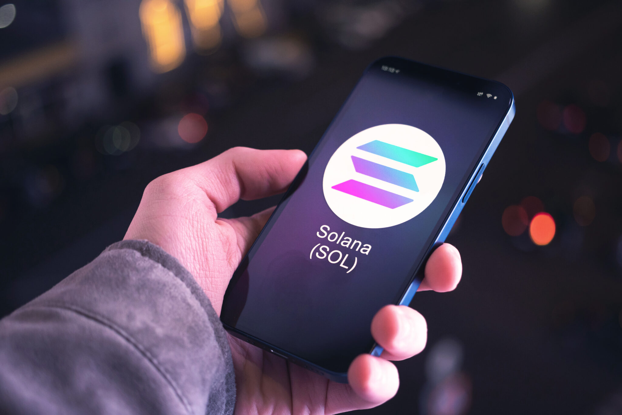 Solana SOL cryptocurrency symbol, logo. Business and financial concept. Hand with smartphone, screen with crypto icon closeup