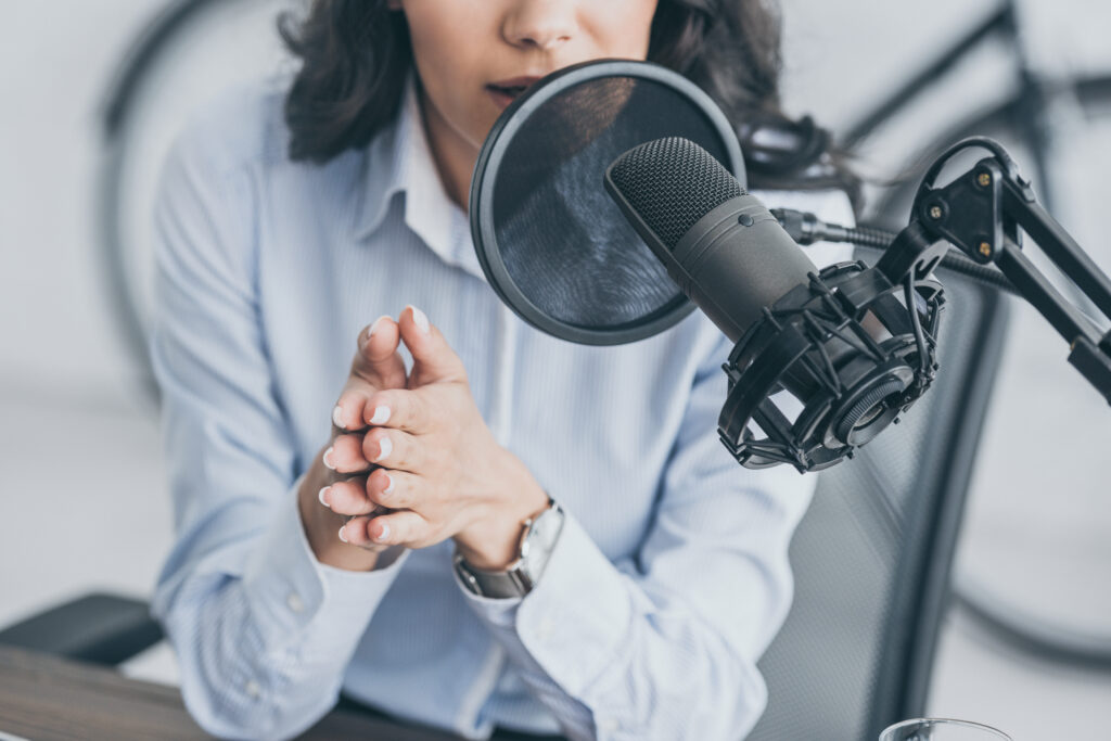 cropped shot of radio host speaking in microphone in broadcasitng studio