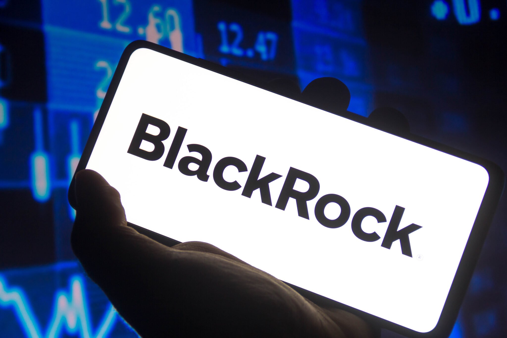 November 15, 2021, Brazil. In this photo illustration the BlackRock logo displayed on a smartphone screen and a stock market graph in the background