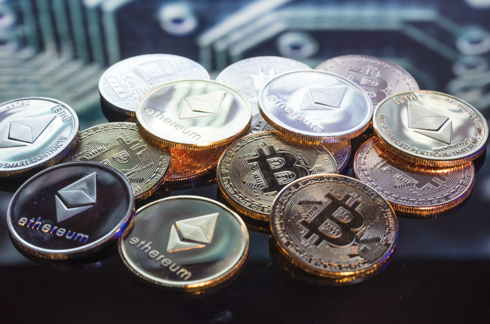 Pièces d'or, d'argent et de cuivre Bitcoin et fond de circuit imprimé défocalisé.  Concept de crypto-monnaie virtuelle.