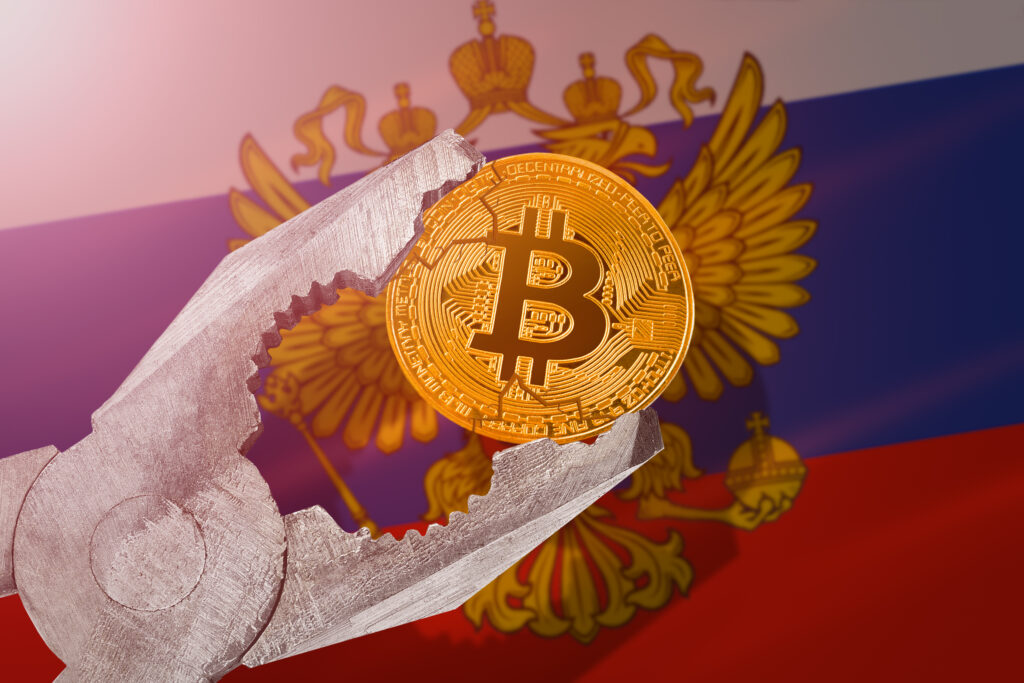 tion in Russia; bitcoin btc coin being squeezed in vice on Russian flag background; limitation, prohibition, illegally, banned