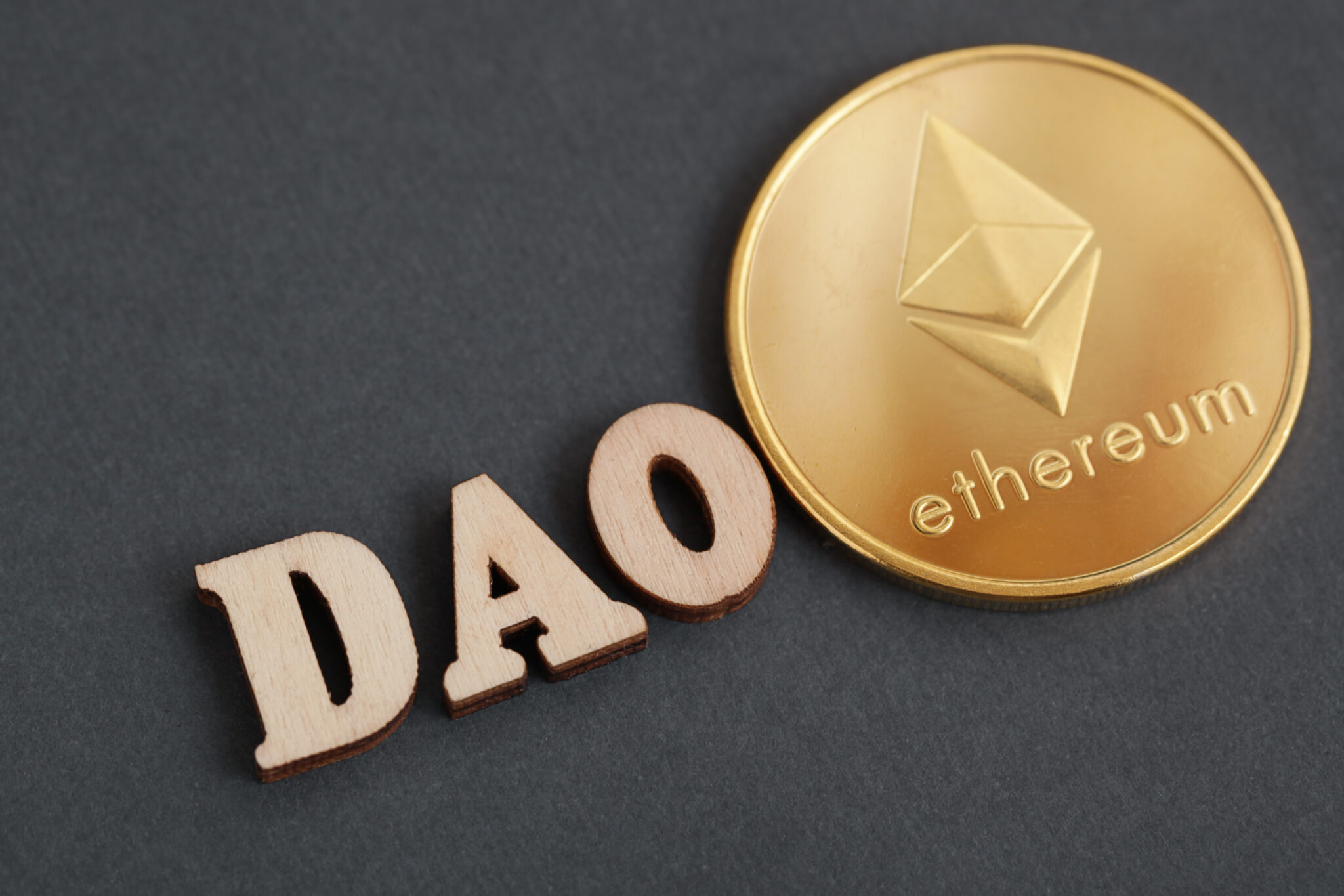 Decentralized Autonomous Organization. DAO, gold coin cryptocurrency Ethereum on dark grey background