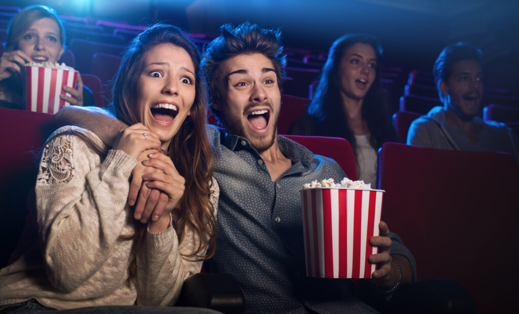 Young couple at the cinema watching an horror movie