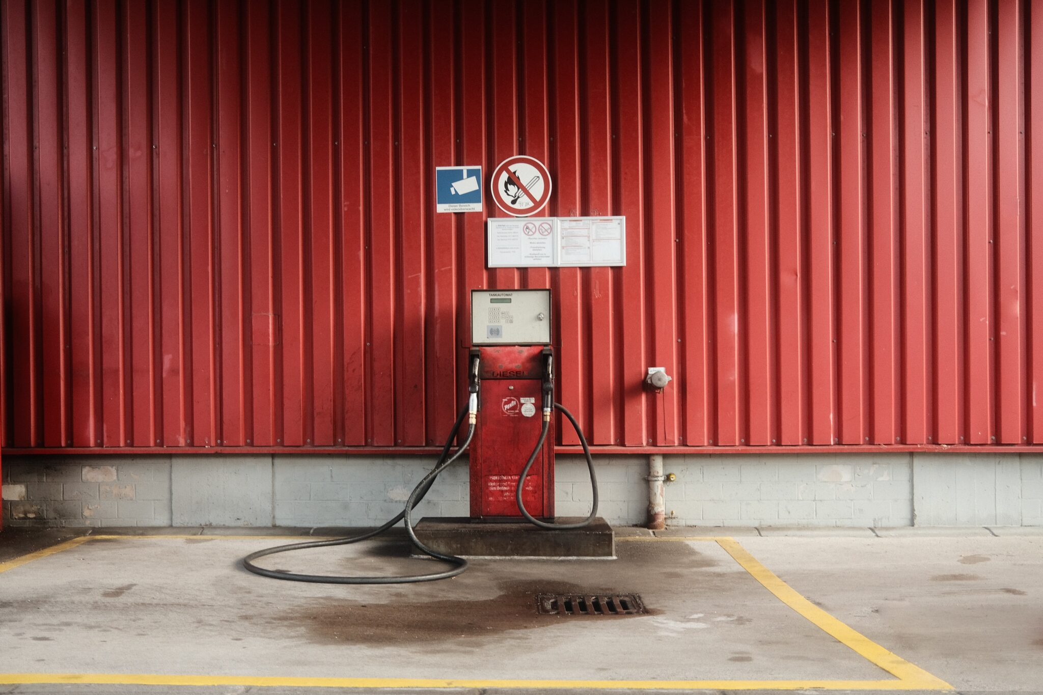 Old fabric fuel station in front of a red wall.