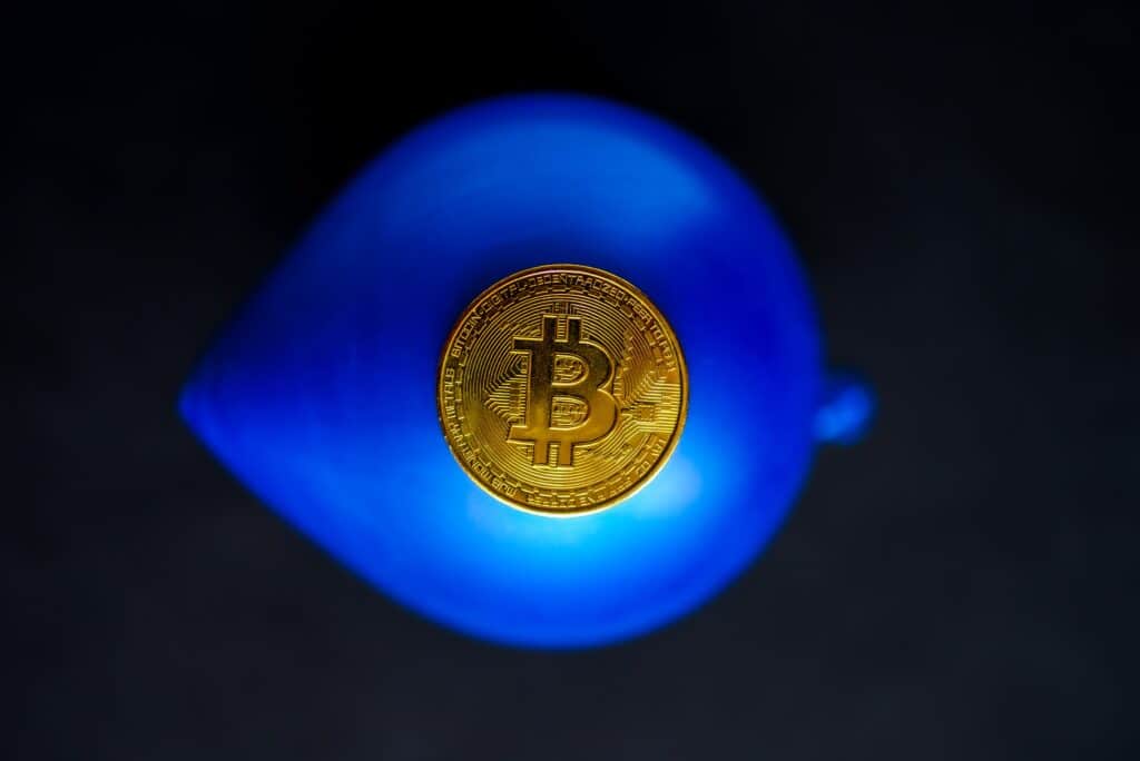 A bitcoin resting on a blue balloon