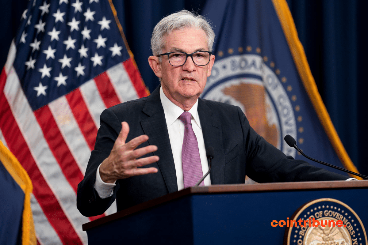 Jerome Powell faisant un discours derrière un pupitre avec un drapeau américain en fond.