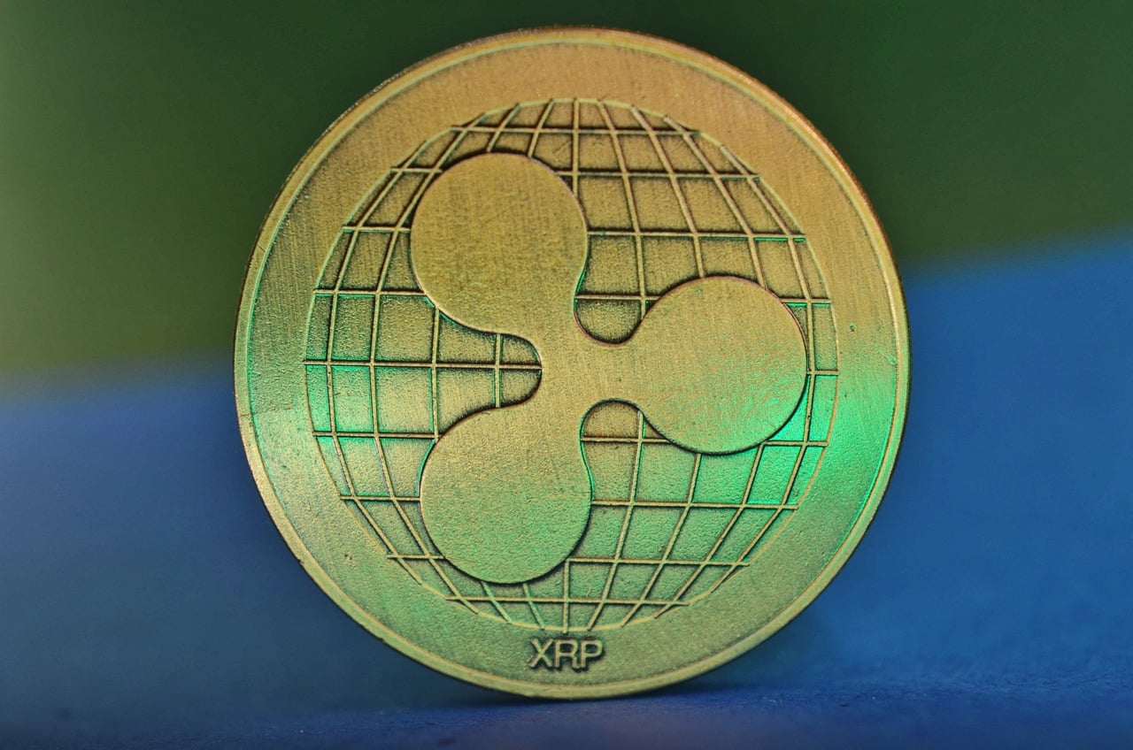 Une pièce de Ripple (XRP), sur fond bleu Le market cap atteint les 20 milliards de dollars