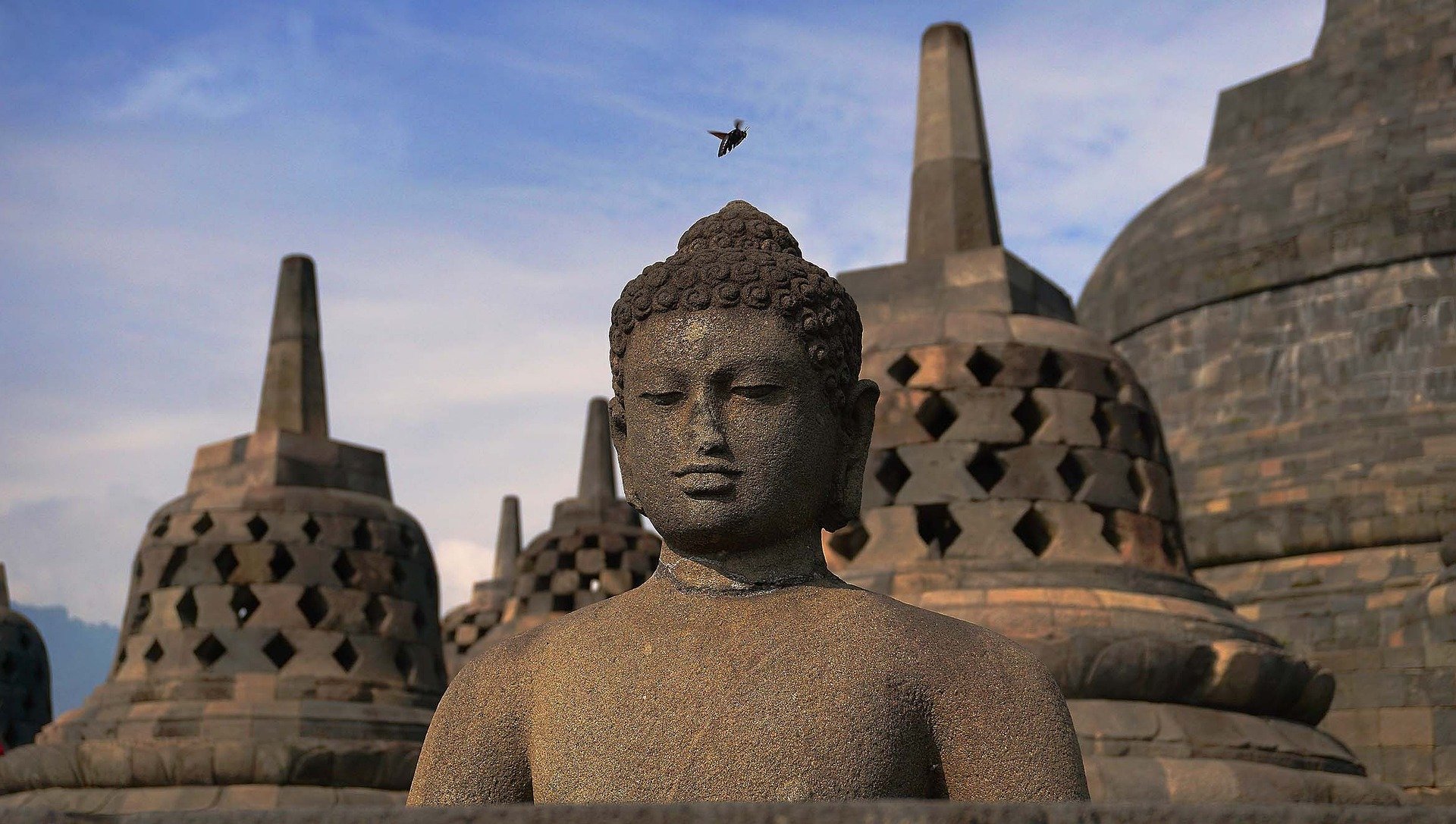 Une statue de bouddha derrière laquelle se trouve des temples bouddhistes