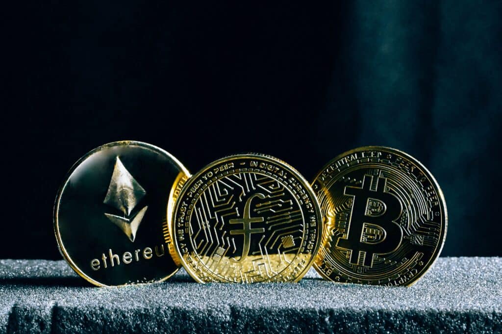 3 pièces représentant le bitcoin et des altcoins