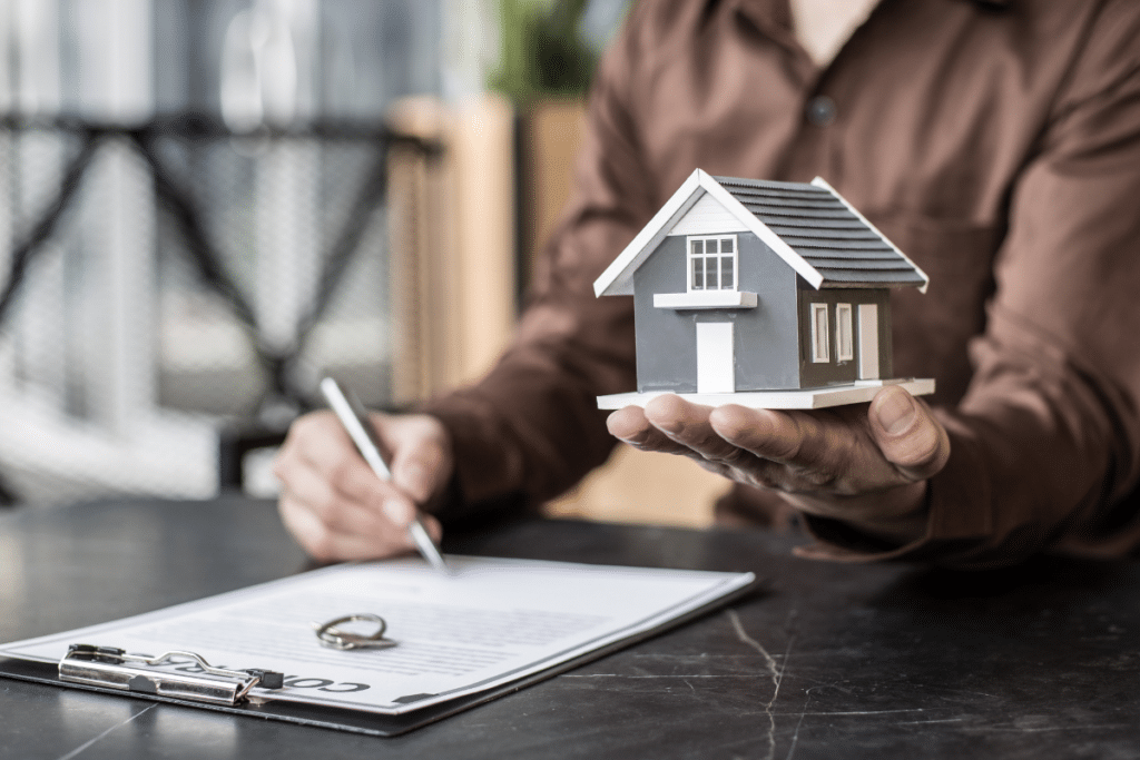 Un agent immobilier tenant dans l'une de ses mains la maquette d'un bien 