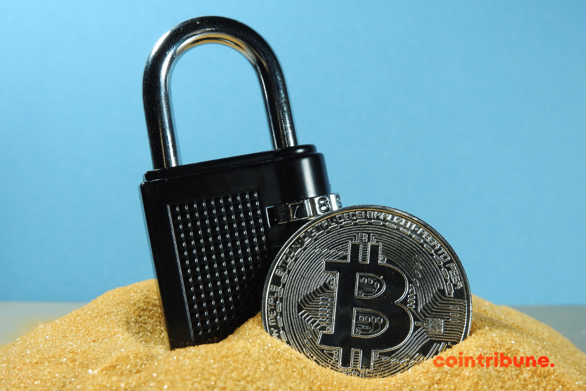 Une pièce de bitcoin à côté d'un cadenas dans le sable