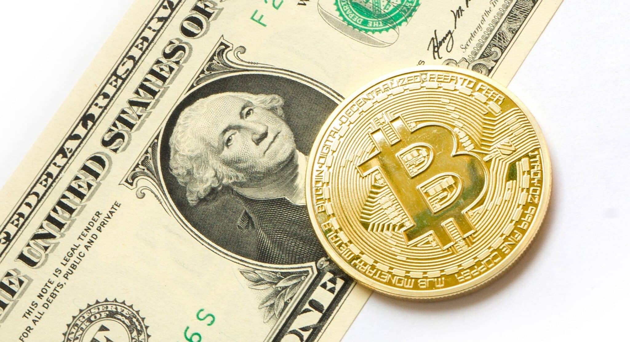 Un bitcoin posé sur un billet d'un dollar