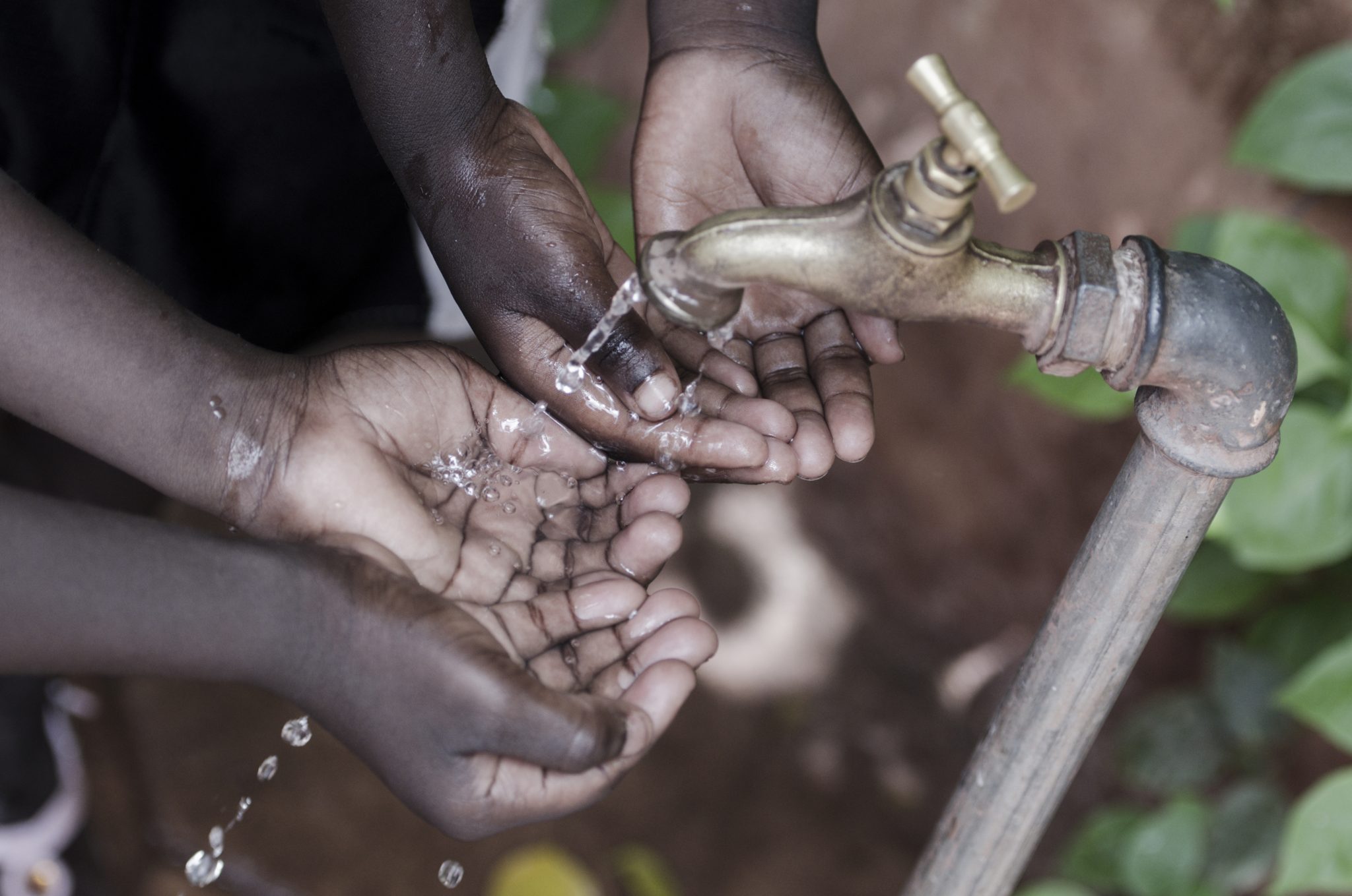 Hands of african children under tap