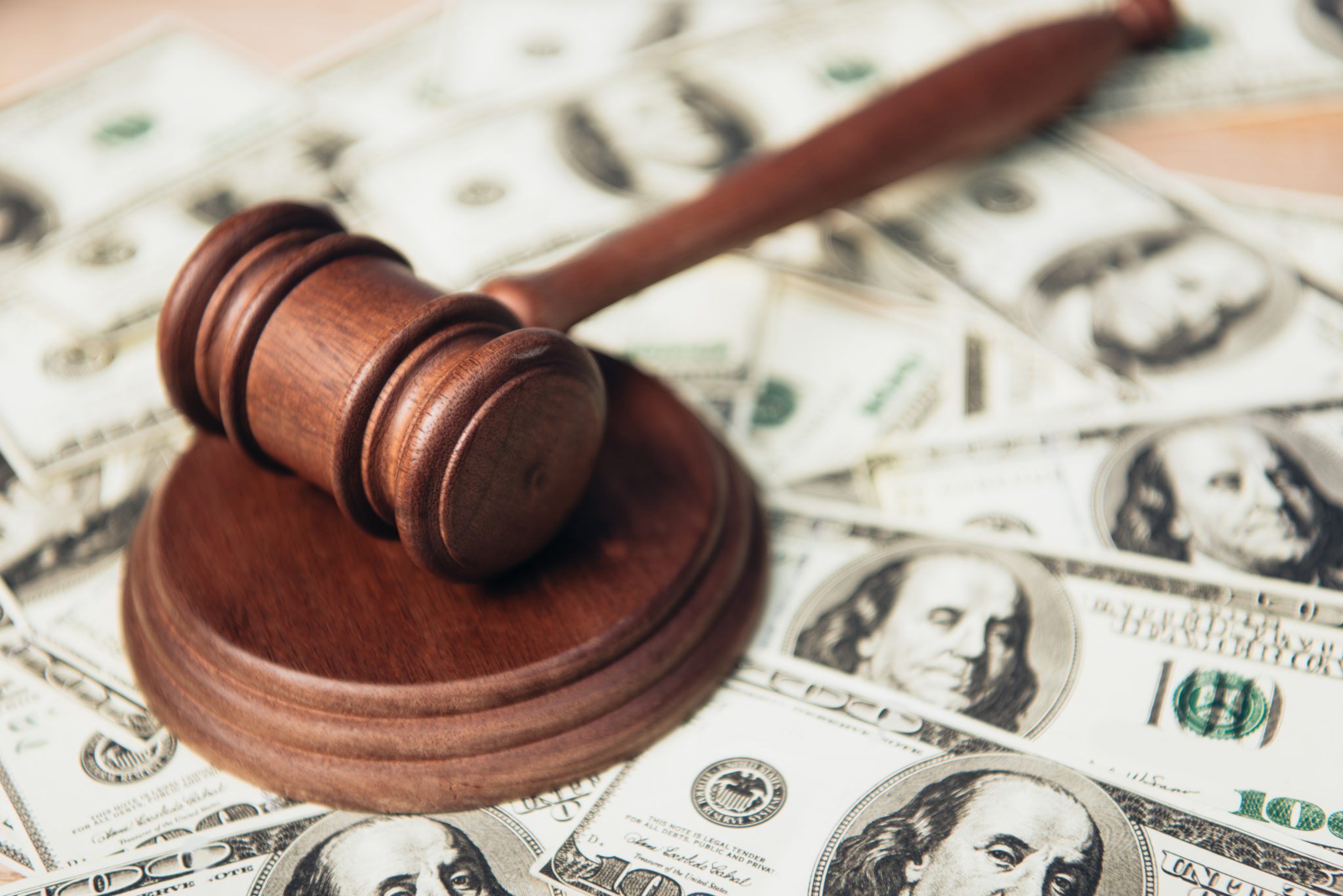 selective focus of wooden gavel near dollar banknotes