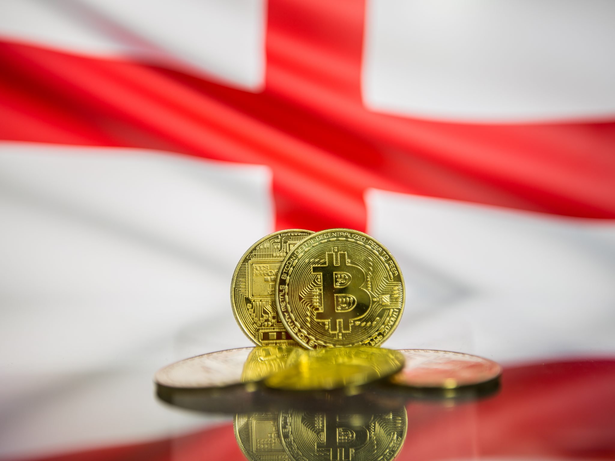 Bitcoin gold coin and defocused flag of England background. Virtual cryptocurrency concept.