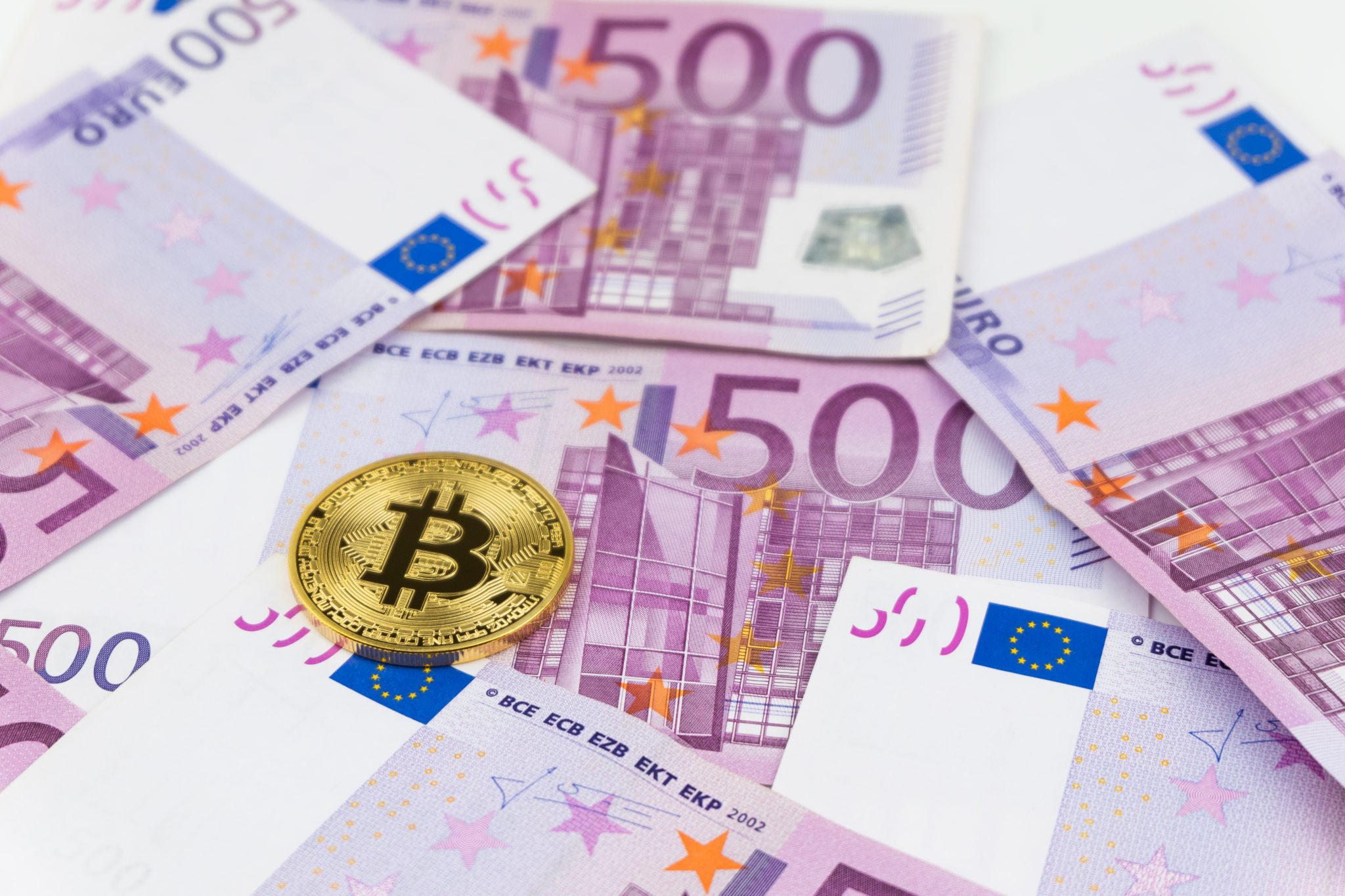 Golden bitcoin on pile of five hundred euro banknotes background. Cryptocurrency, digital currency with euro money bills. Bitcoin exchange and accepted to payment, Finance and technology concept.