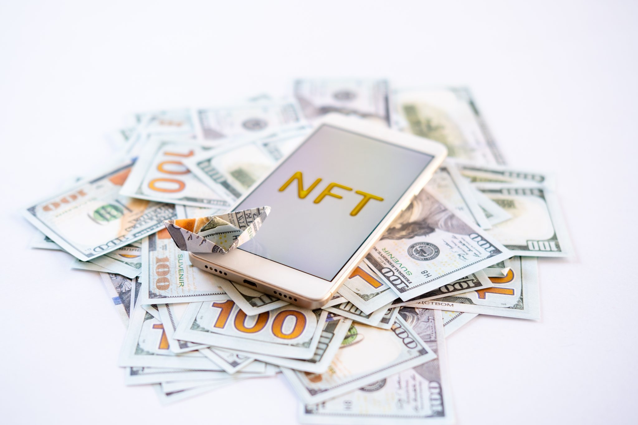 Non-fungible token NFT, crypto art, digital art, new type of cryptorurrency. Cell phone with golden NFT text in golden frame as art object on dollars background